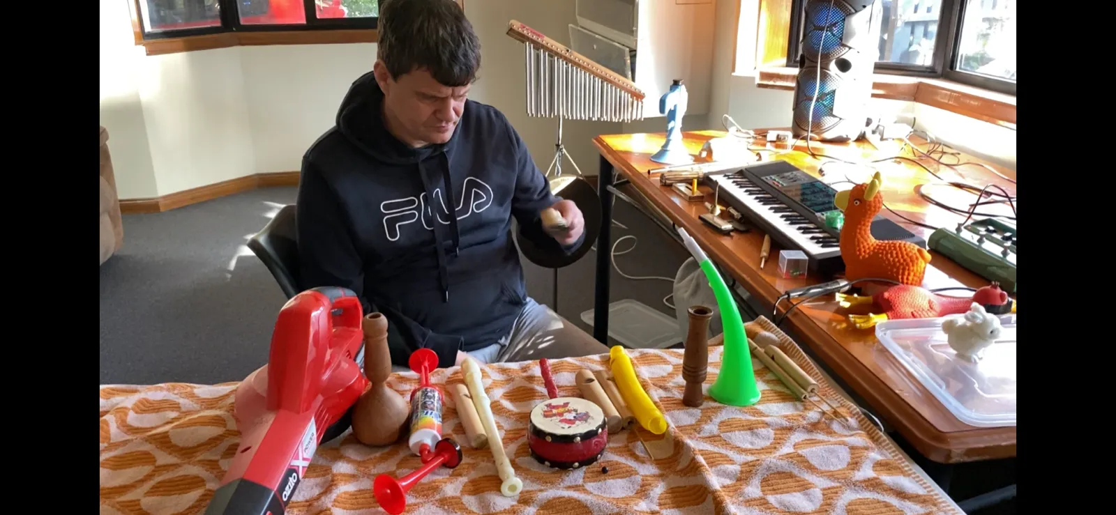 A young man plays with toy instruments and percussion laid out on a table